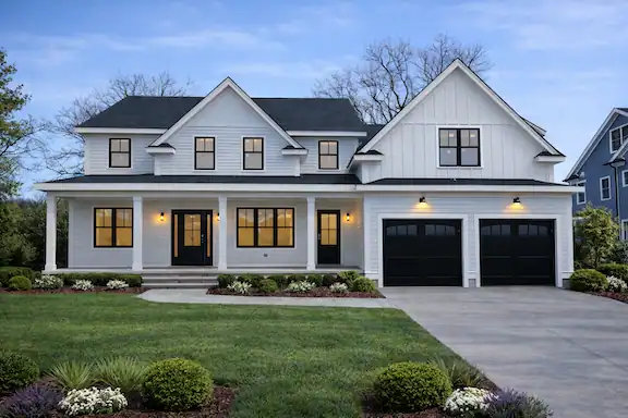 Beautiful modern white family home with black garage doors and large windows.