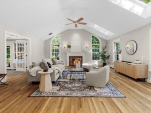 Vaulted living room with skylights, arched windows, hardwood floors, fireplace, neutral seating, and natural light at 45 South Street in Needham MA