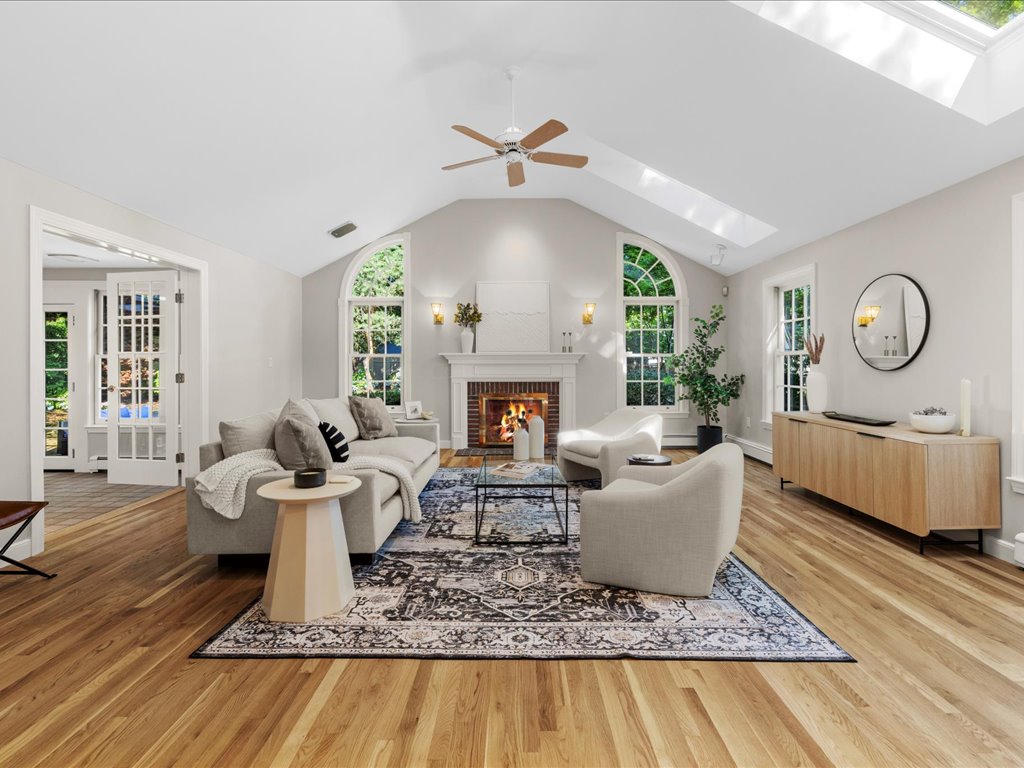 Vaulted living room with skylights, arched windows, hardwood floors, fireplace, neutral seating, and natural light at 45 South Street in Needham MA