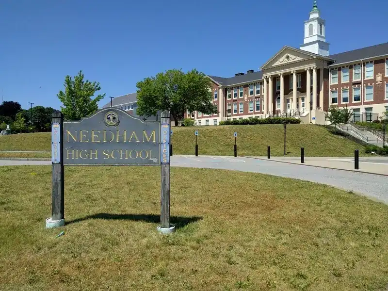 Historic Needham High School building with classic architecture and well-maintained grounds.