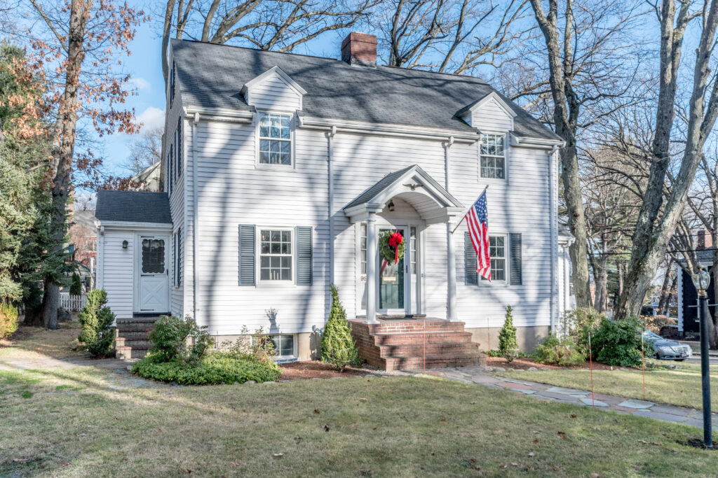 White Colonial-style home in Needham, MA, featuring classic architecture, symmetrical windows, and a welcoming front entrance.