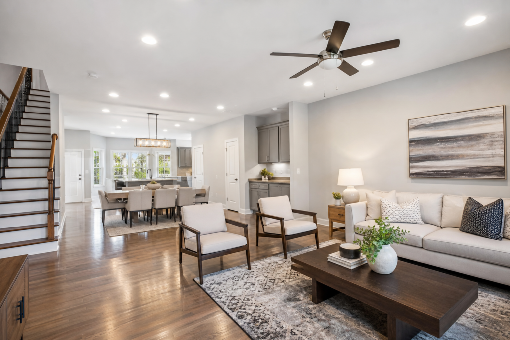 Open concept living room with hardwood floors, staircase, and view to dining area and kitchen