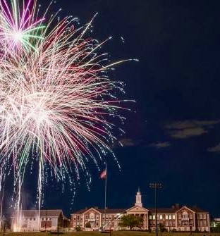 Colorful Fourth of July fireworks lighting up the night sky above the Needham High school building.