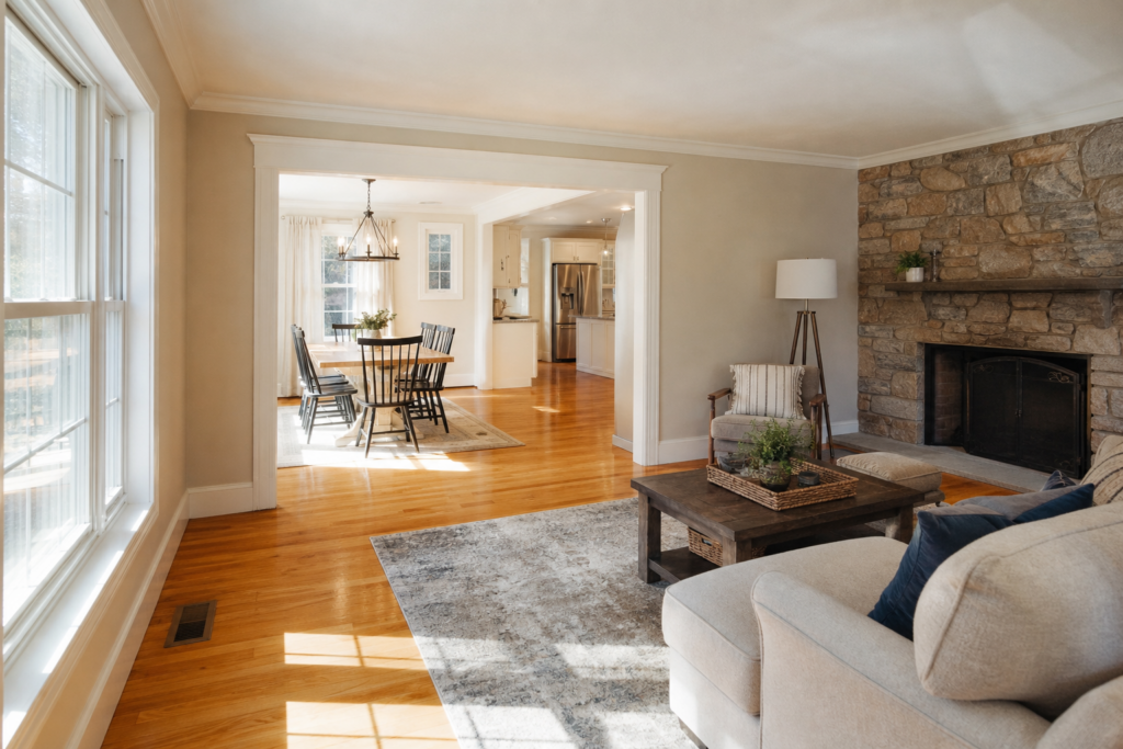 Living room with stone fireplace and open sightline to dining area and kitchen in Boston Metrowest, MA
